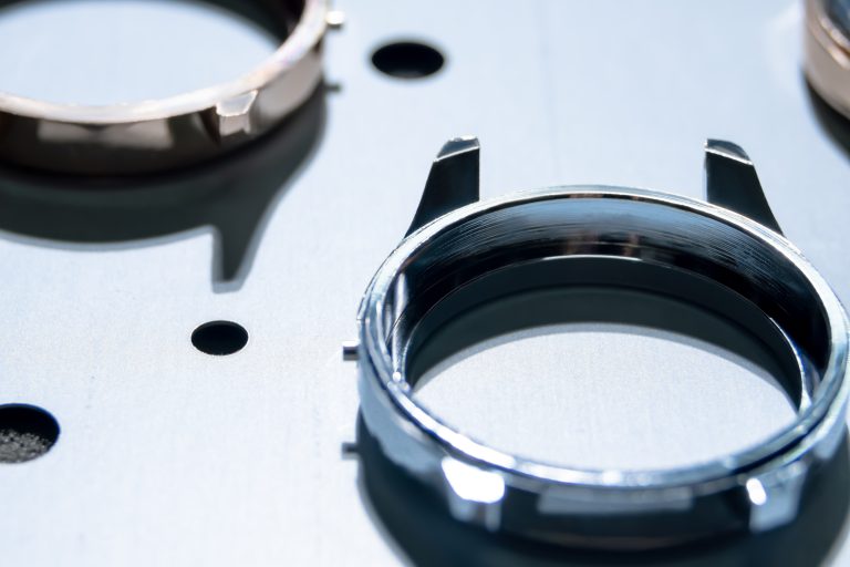 Close up of shiny stainless steel watch case warm up inside vapor deposition machine, PVD coating to harden wristwatch frame, increase durability and  acquire golden titanium luxury look