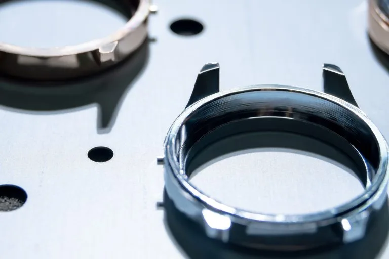 Close up of shiny stainless steel watch case warm up inside vapor deposition machine, PVD coating to harden wristwatch frame, increase durability and  acquire golden titanium luxury look